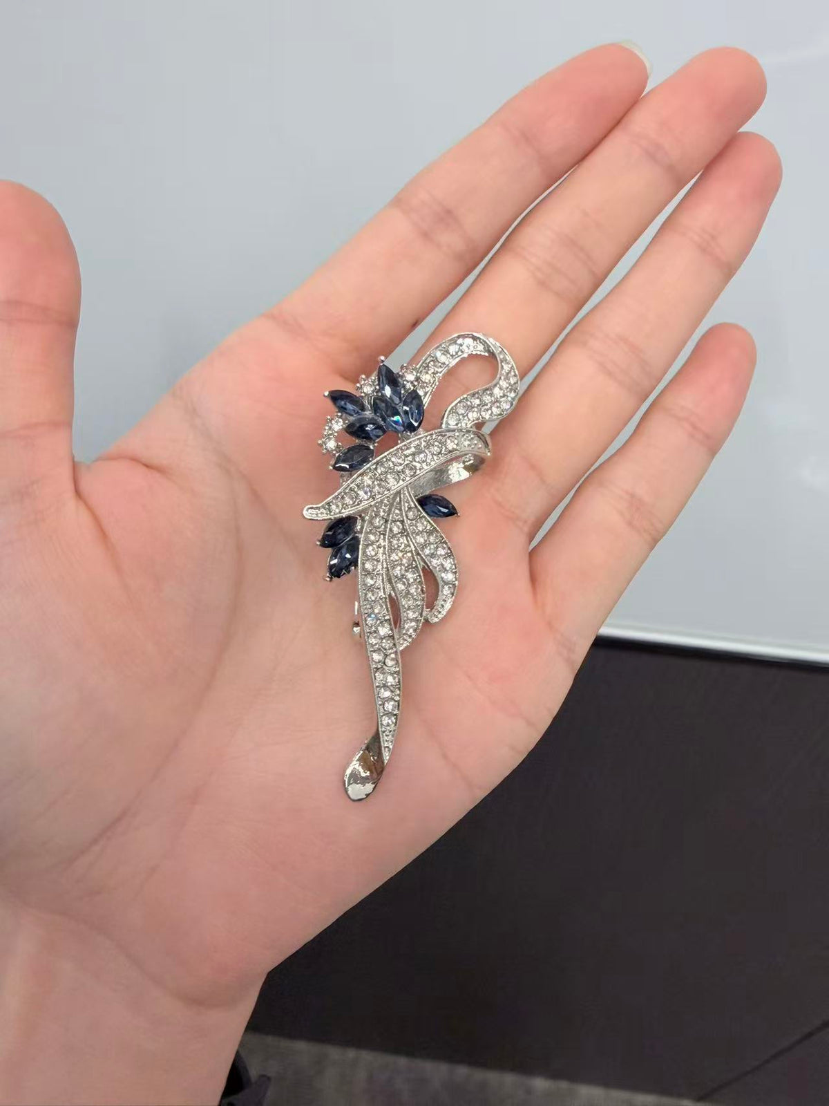 Crystal floral brooch pin held in hand to show actual size