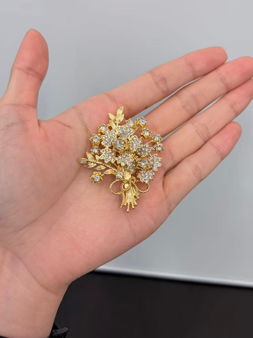 Crystal flower bouquet brooch pin held in hand to show actual size
