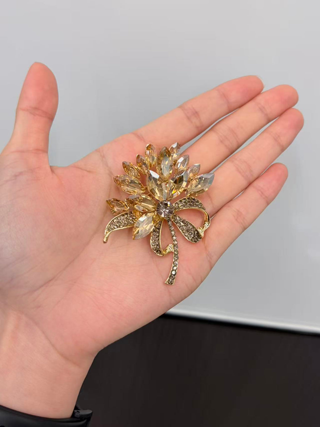 Crystal flower bow brooch pin held in hand to show actual size