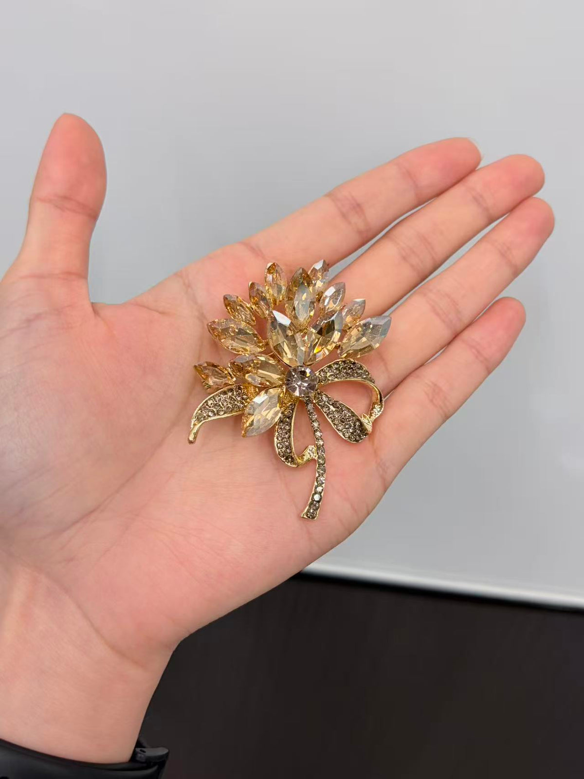 Crystal flower bow brooch pin held in hand to show actual size