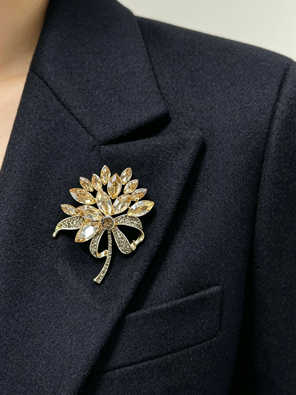Crystal flower bow brooch pin worn on a dark suit lapel