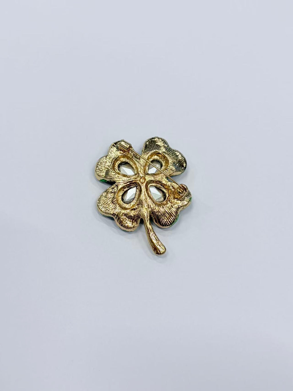 Crystal four leaf clover brooch pin back view on gray background