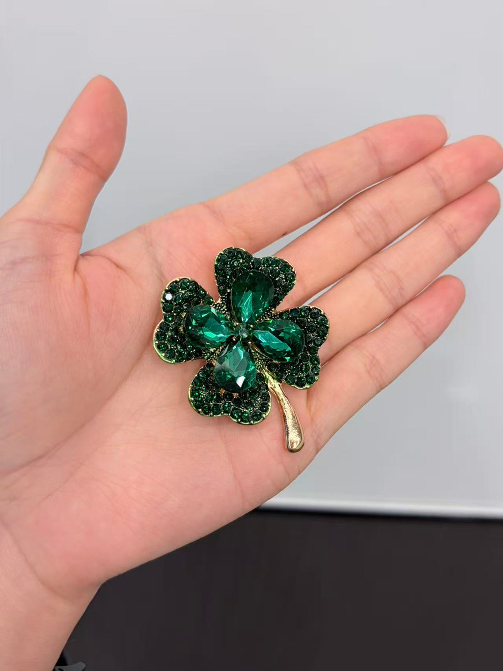 Crystal four leaf clover brooch pin held in hand to show actual size