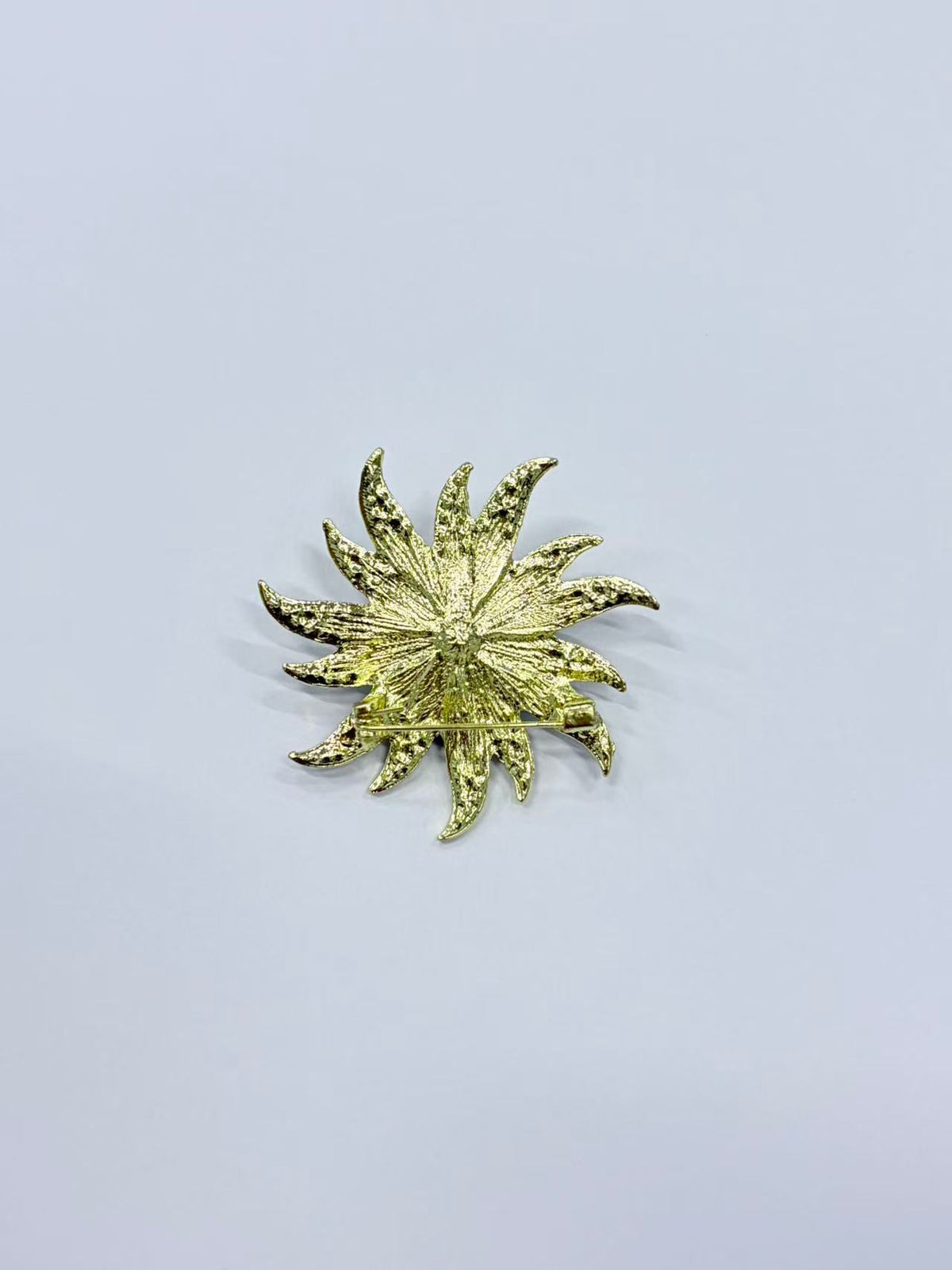 Crystal sunburst brooch pin angled view on gray background