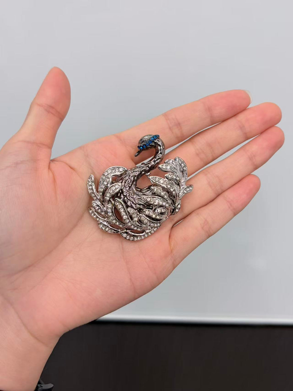 Crystal swan brooch pin held in hand to show actual size