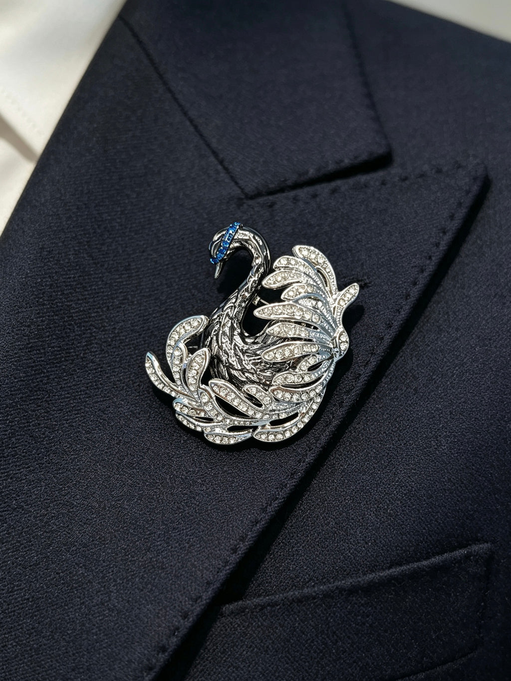 Crystal swan brooch pin worn on a dark suit lapel