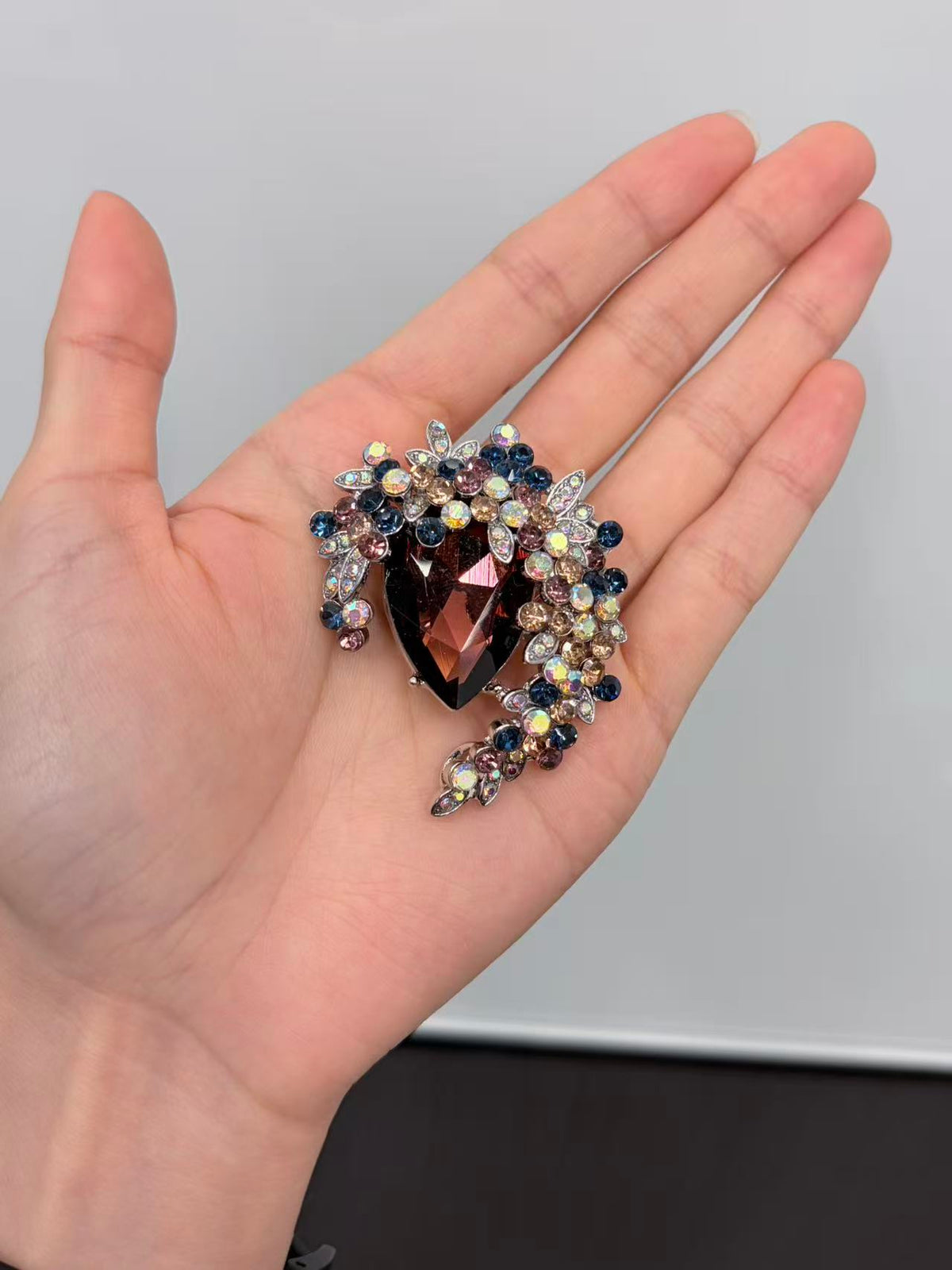 Crystal teardrop floral brooch pin held in hand to show actual size